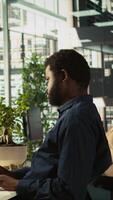 Vertical Employee reviewing financial charts at desk in modern office, analyzing business performance metrics. Professional at work looking over data trends and strategic insights, camera B video