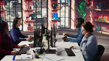 Call center agent helping customers regain access to accounts, resetting passwords. Employee in customer center workspace assisting clients needing help, providing helpful solutions, camera B video