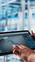 Vertical Industry 4.0 industrial plant engineer designs new robotic machines using CAD software on tablet. Smart factory technician using digital device app to do tooling for automation equipment, camera A video