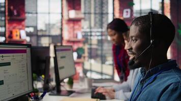 Diverse customer center workers assisting clients with installing software. Multiethnic team of call center agents using remote access tools to connect to customer devices, fixing errors, camera B video