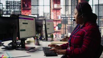 Call center agent listening to customer needs, providing step by step guidance. Customer center worker manages incoming and outgoing calls, walking clients through technical solutions, camera B video