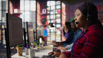 IT support expert at PC in call center office troubleshoots errors to minimize downtime. Tech support agent at desk writing code, maintaining technical systems and infrastructure, camera B video