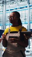 Vertical Smart factory team leader talking with employees overseeing operation of robotic arms on facility floor. Industry 4.0 plant workers doing brainstorming regarding troubleshooted errors, camera A video