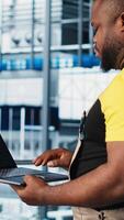 Vertical Industry 4.0 industrial plant specialist designs new robotic machines using CAD software on laptop. Smart factory technician using notebook to do tooling for automation equipment, camera A close up video