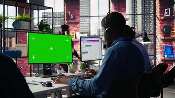 Technical support specialist in call center office doing troubleshooting using green screen computer. IT worker fixing customer connectivity issues using chroma key mockup PC, camera B video