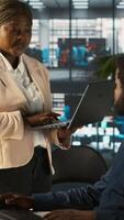 Vertical Worker in office receiving feedback from management executive looking over work done on laptop. African american manager in workspace giving tasks to employee, providing necessary data, camera A video