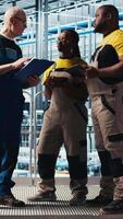 Vertical Photovoltaics smart factory team leader and workers analyzing data. Senior engineer and coworkers in industry 4.0 solar panels plant producing renewable energy review system metrics, camera A video