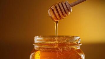 Golden honey jar with dipper drizzling against warm background photo