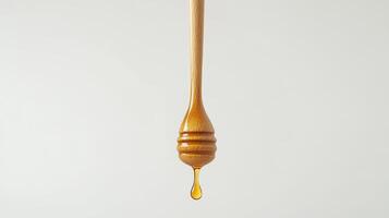 Honey dripping from wooden dipper against light background photo
