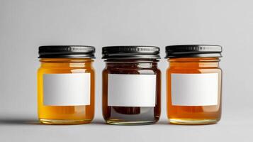 Three assorted glass jars with blank labels on gray background photo
