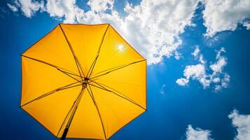 Bright yellow umbrella against blue sky with white clouds photo