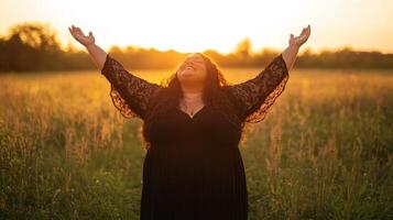 Hispanic female embracing sunlight in field at sunset photo