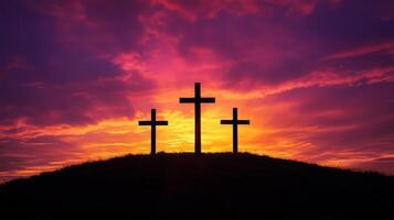 Three crosses silhouetted against vibrant sunset sky on hilltop photo