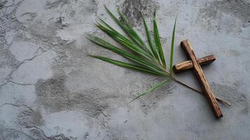 Wooden cross and palm leaf on concrete surface symbolizing christianity and peace photo