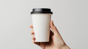 Hand holding blank white coffee cup with black lid on gray background photo
