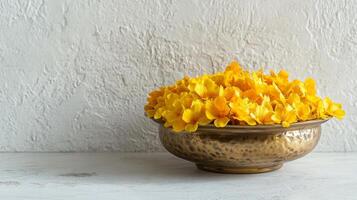 Minimalist arrangement of golden yellow flowers in hammered brass bowl for elegant decor.Vishu day photo
