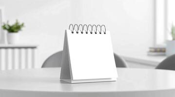 A white notebook on a table in front of a window photo