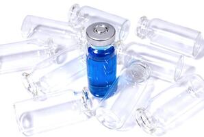 Flacon with blue vaccine and heap of empty bottles photo