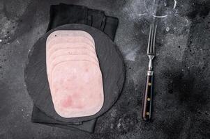 Thinly sliced ham arranged beautifully, perfect for sandwiches, charcuterie boards, or gourmet meals. black background. top view photo