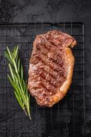 Juicy grilled striploin New York steak with perfect grill marks, ideal for a hearty meal or summer barbecue. black background. top view photo