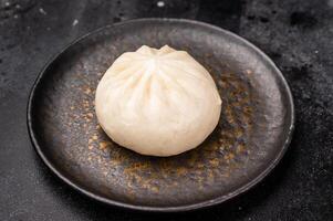 Steam Bao bun with meat on plate with chopsticks. black background. top view photo