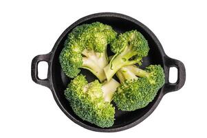raw broccoli pieces in a skillet isolated on white background. top view photo
