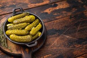 Artisan Pickled Gherkins, pickled cucumbers, beautifully arranged and ready to elevate your culinary creations with their bold taste. wooden background. top view photo