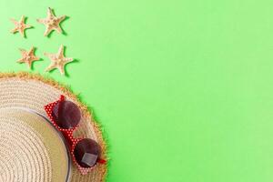 Summer holiday background straw hat seashells on green background top view with copy space photo