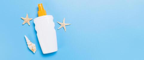 sunscreen cream banner with starfish and seashells in bottles on blue background, top view photo