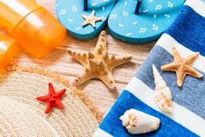 flip flops, straw hat, starfish,sunscreen bottle, body lotion spray on wooden background top view . flat lay summer beach sea accessories background, vaation concept photo