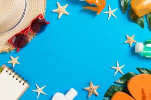Beach accessories with straw hat,sunscreen bottle and seastar on blue background top view with copy space photo