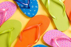 many colored flip flops on yellow background.Copy space top view photo