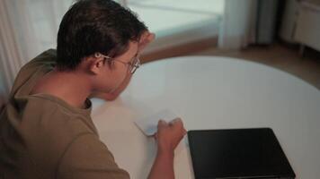 Focused study a young person intensely reviewing documents at a table, showcasing dedication and concentration. A laptop rests beside them, suggesting a blend of digital and physical work. video