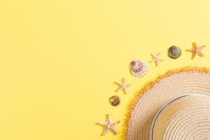 Beach hat with seashells brown yellow table. summer background concept with copy space top view photo