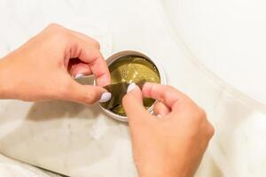 Female hands taking eye patches out from the container with the tweezers.Anti aging concept photo