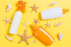 Sunscreen bottles with seashells yellow table top view photo