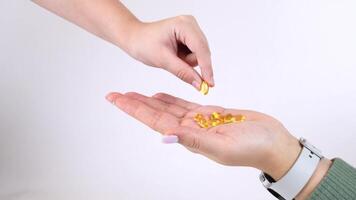 Hand holding golden capsules with pill dropping into palm in smooth motion sequence video