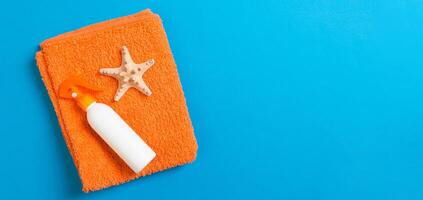 Summer beach flat lay accessories. Sunscreen bottle cream, towel and seashells colored banner Background. Travel holiday concept with copy space photo