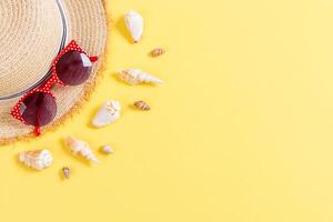 Summer holiday background with straw hat seashells yellow background top view with copy space photo