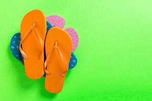 A lot of colored flip flops on green background Top view with copy space photo