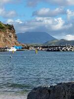 Scenic tropical marina with boats and mountain view under cloudy sky photo