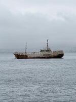 Abandoned Rusty Ship Floating in Foggy Coastal Waters photo