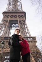 Happy couple poses together near the Eiffel Tower in Paris, creating a romantic memory in the iconic French city. photo