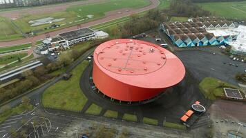 Aerial View of Red Circular Building Surrounded by Green Fields. photo