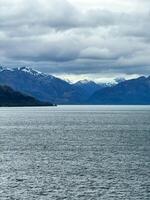 Snow-Capped Mountains and Deep Fjord Under Cloudy Sky in Remote Wilderness photo
