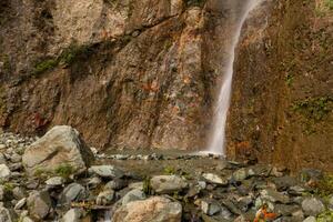 Small waterfall flowing down a rocky cliff in a serene mountain setting photo