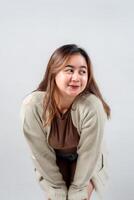 A young woman in a cozy sweater leans forward with a curious and playful expression, looking to the side against a neutral background photo