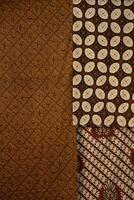 Traditional batik fabrics with intricate patterns in brown, beige, and black tones. Authentic Indonesian textile with cultural motifs, perfect for backgrounds and design elements. photo