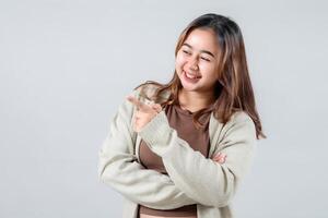 A young woman smiles brightly while pointing to the side, presenting something interesting. Her casual style and engaging expression make this image ideal for lifestyle and promotional projects photo