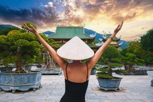back of happy girl tourist traveler at a Buddhist temple at Linh Ung Pagoda in Da Nang in Vietnam at sunset. Concept of travel and tourism in Asia photo